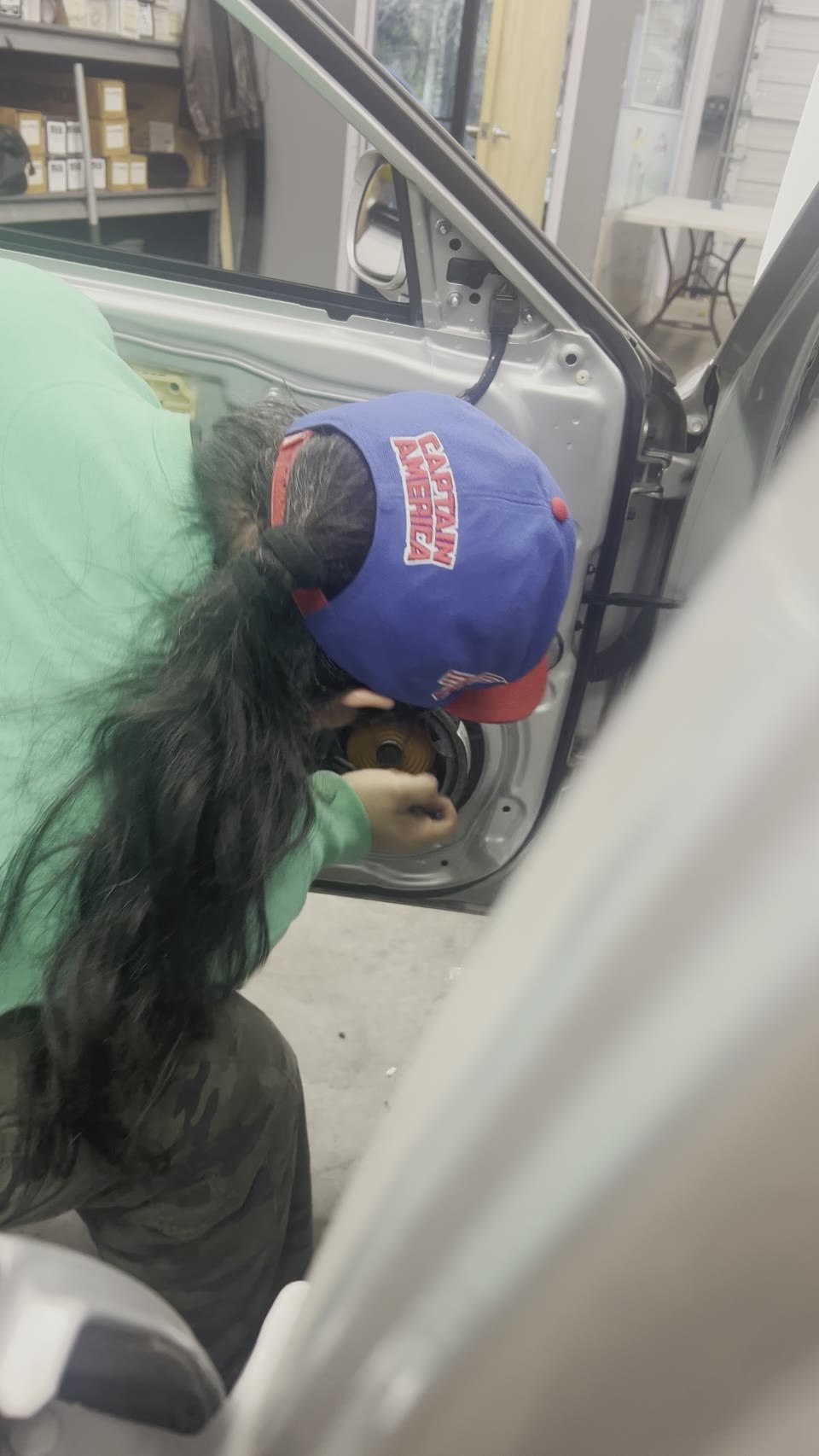 Technician installing an upgraded speaker inside a vehicle door