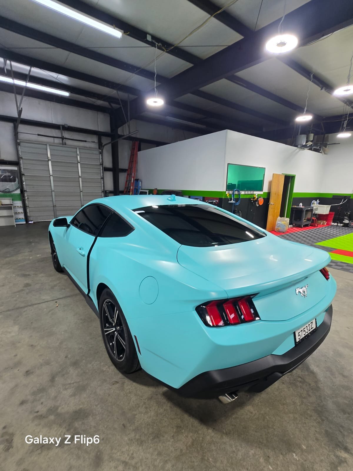Rear three-quarter view of a mint satin wrapped Ford Mustang