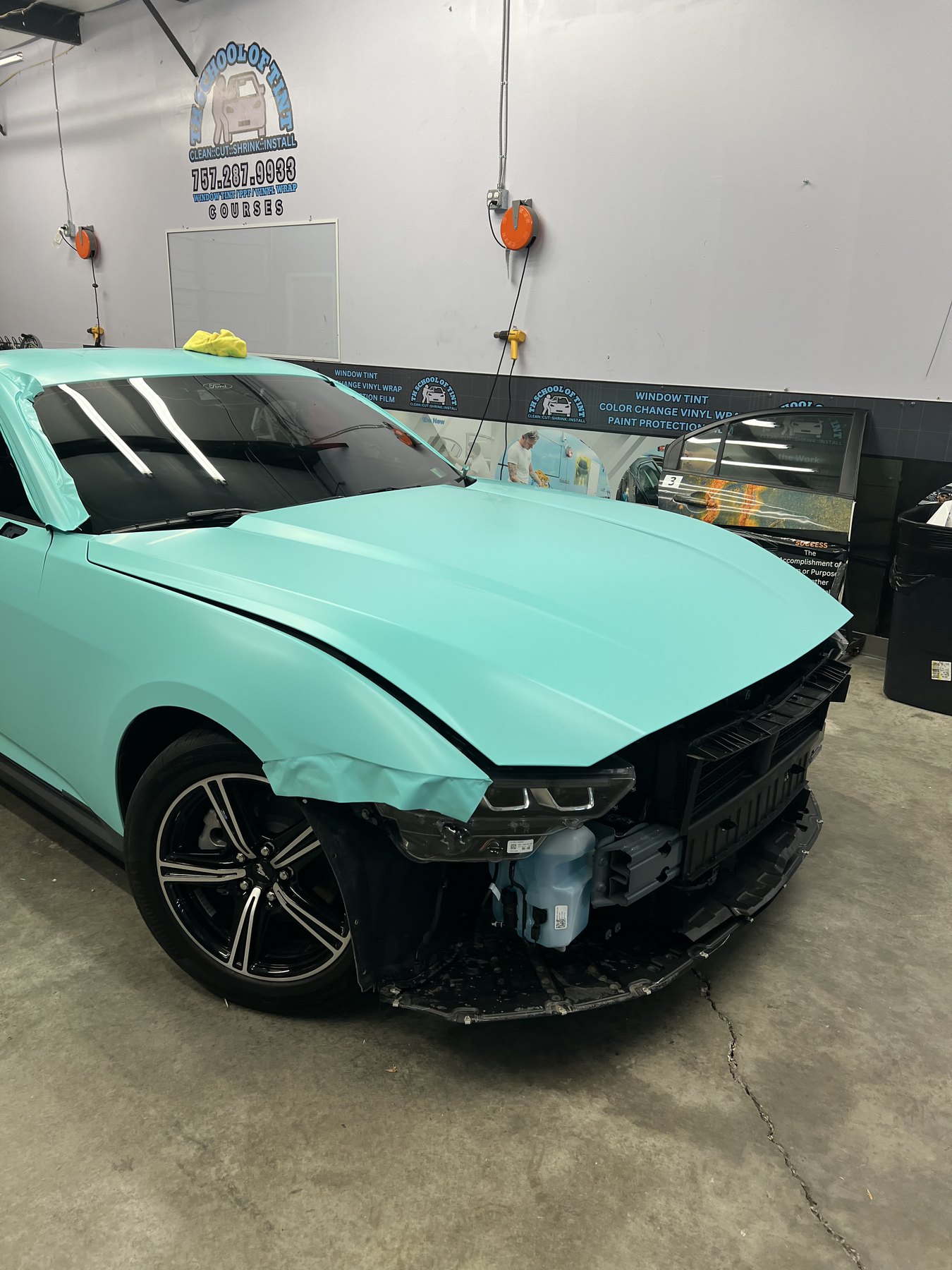Mint vinyl being installed across the front panels of a Ford Mustang