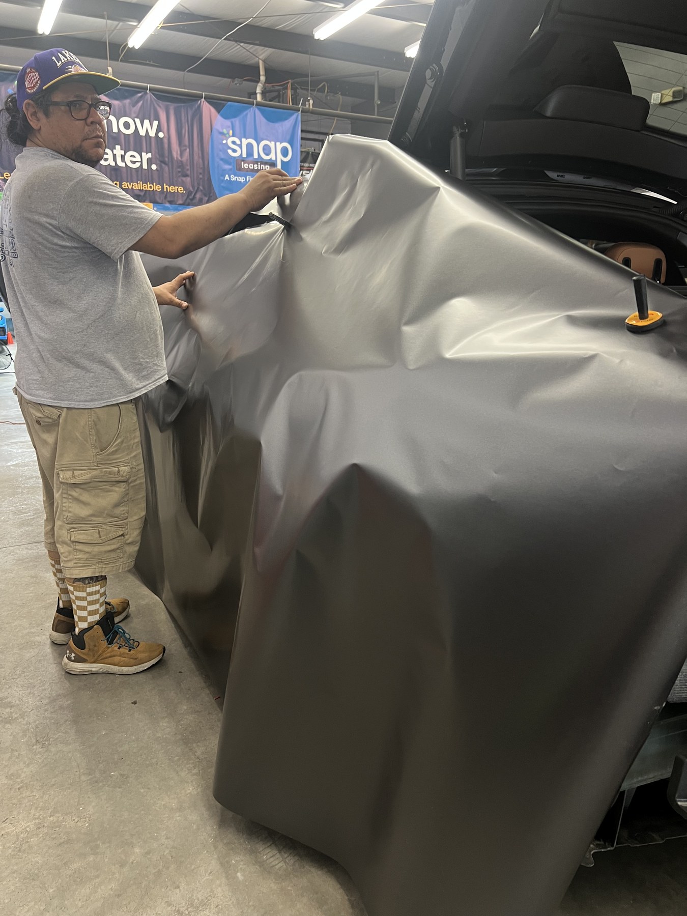 Large sheet of vinyl being positioned during a vehicle wrap installation